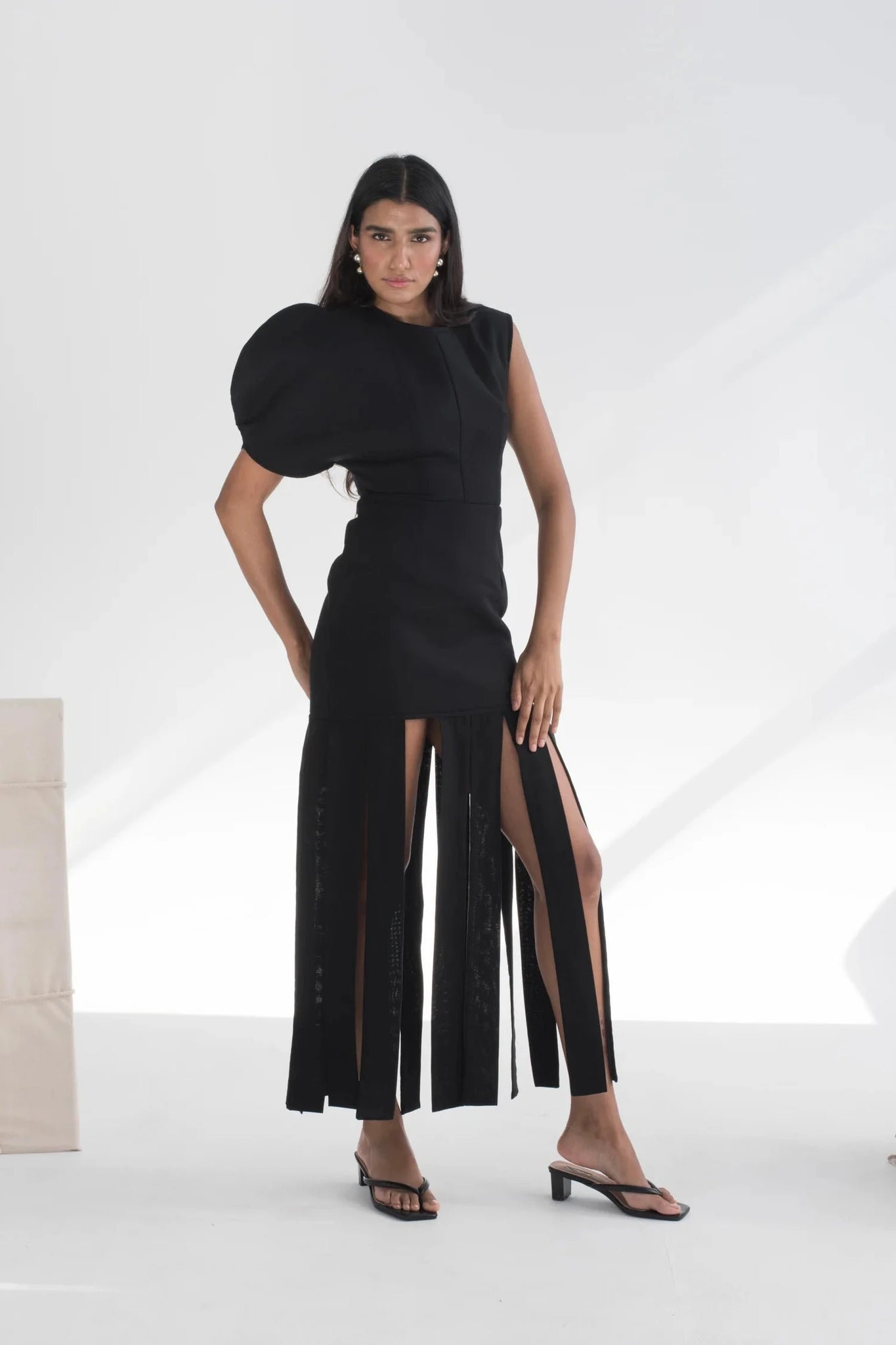 Woman wearing a black dress with a slit on a white background