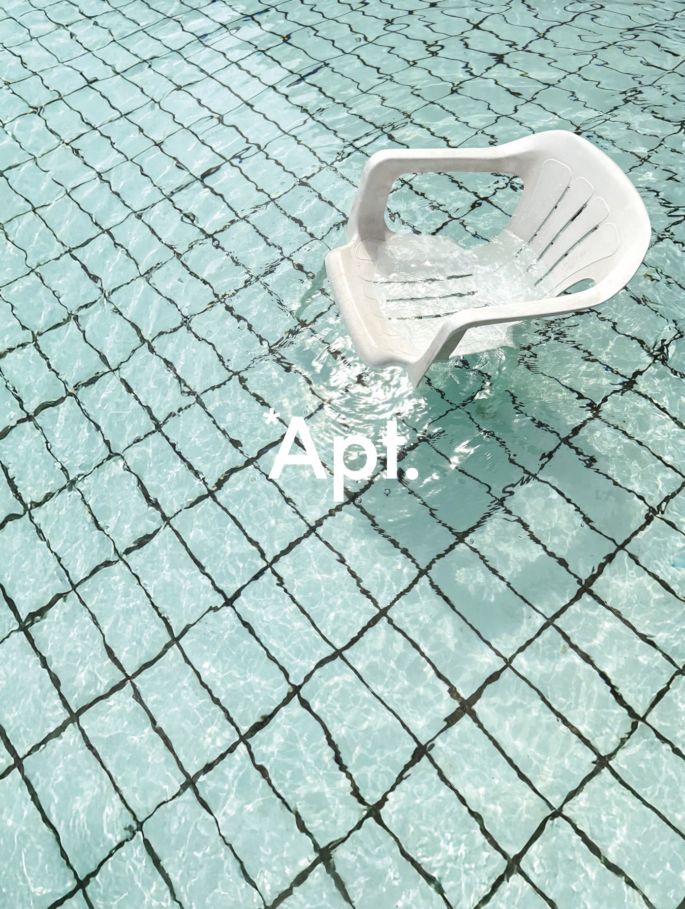 White chair partially submerged in water with 'Apt.' text overlay on a tiled pool floor.