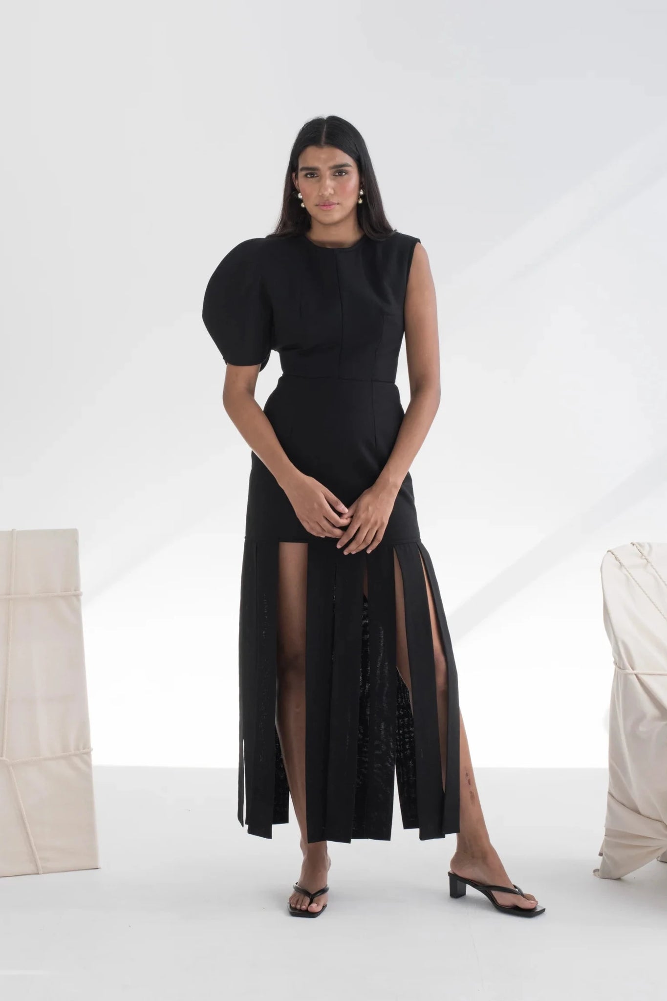Woman wearing a black dress with sheer panels in a minimalistic setting