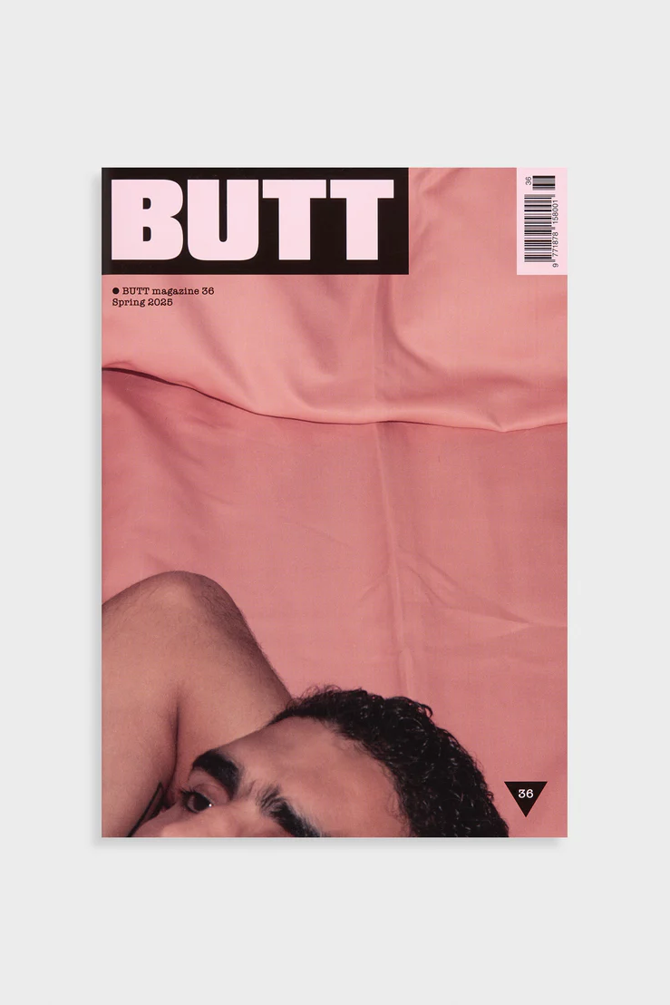 Magazine cover with a person lying on pink fabric, featuring the word 'BUTT' at the top.